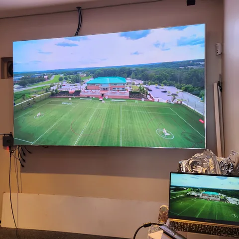 Indoor-LED-Wand in einem Geschäftsraum mit Luftaufnahme eines Sportplatzes