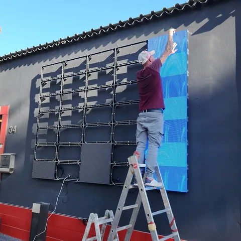 Montage einer Outdoor-LED-Wand an einer Fassade: Module werden von der Leiter aus gesetzt