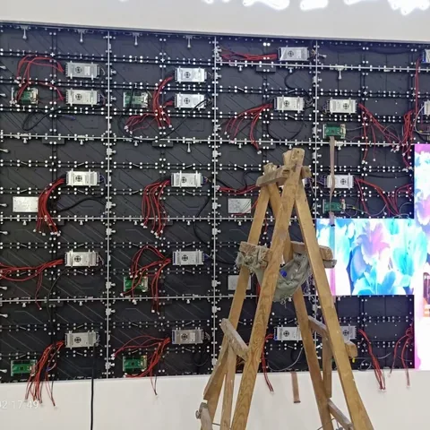 Montage einer Indoor-LED-Wand: offene Modulrückseiten mit Verkabelung, davor die Leiter