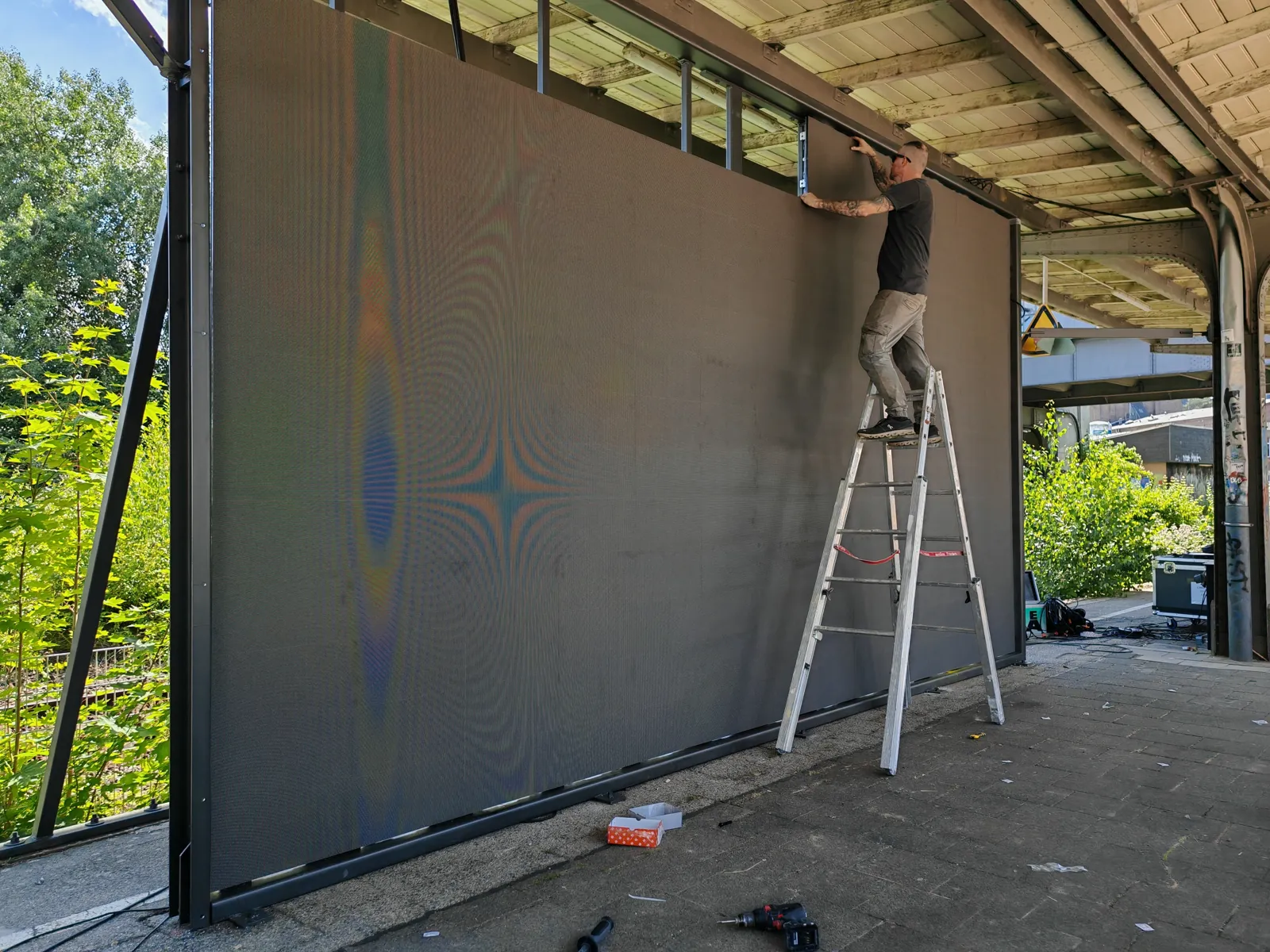 Aufbau einer Outdoor-LED-Wand: Monteur auf der Leiter richtet die Module aus