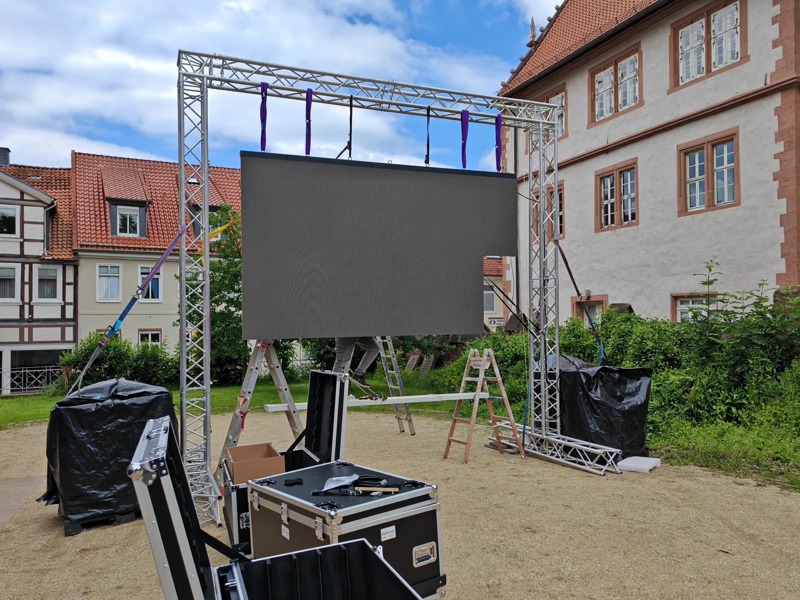 Gemietete LED-Wand an einer Traversenkonstruktion im Freien, Flightcases daneben